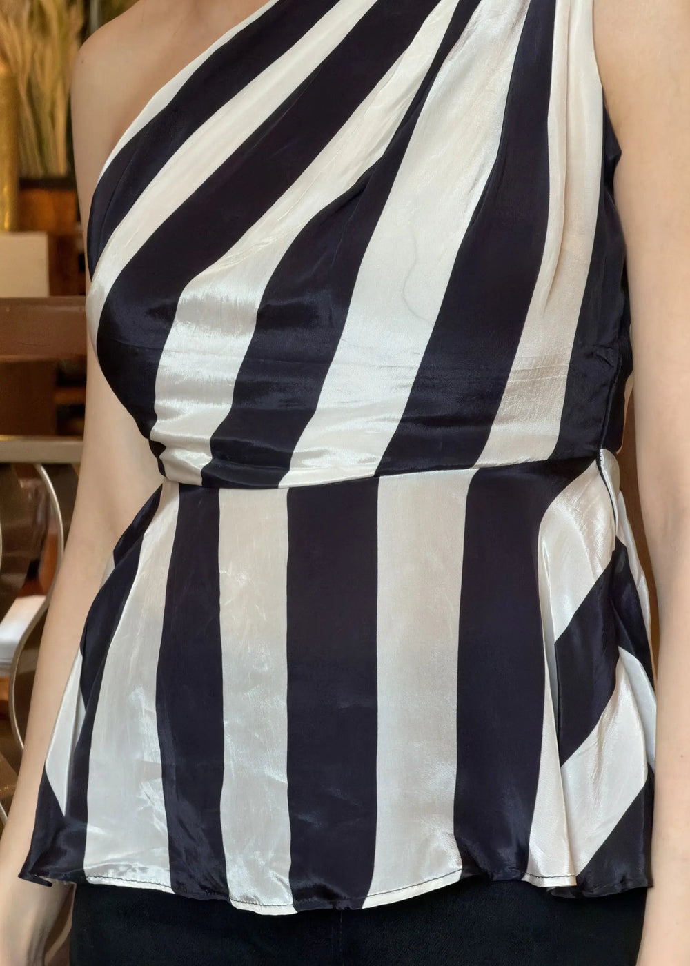 Black and white striped one-shoulder top worn by a person indoors.