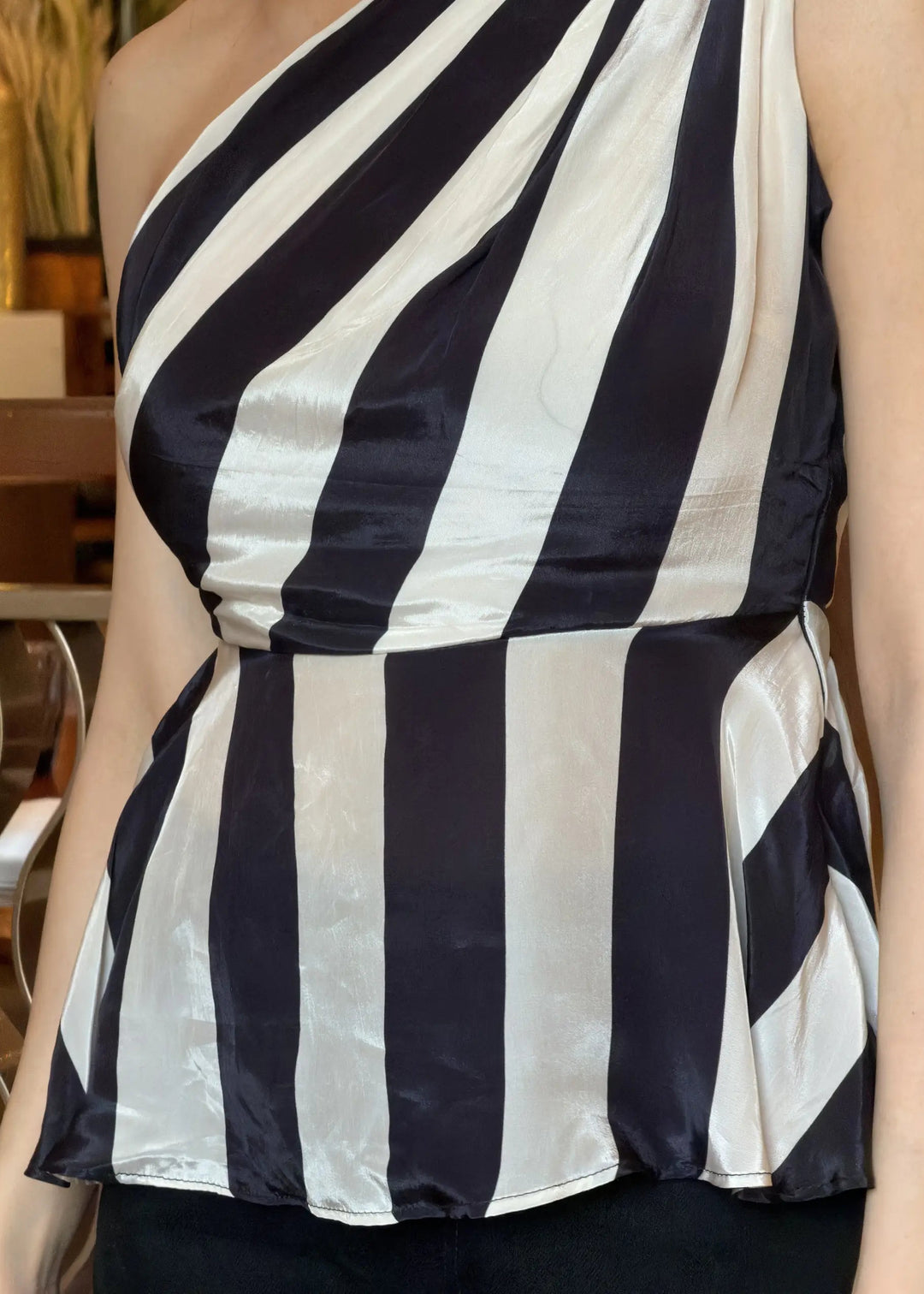 Black and white striped one-shoulder top worn by a person indoors.
