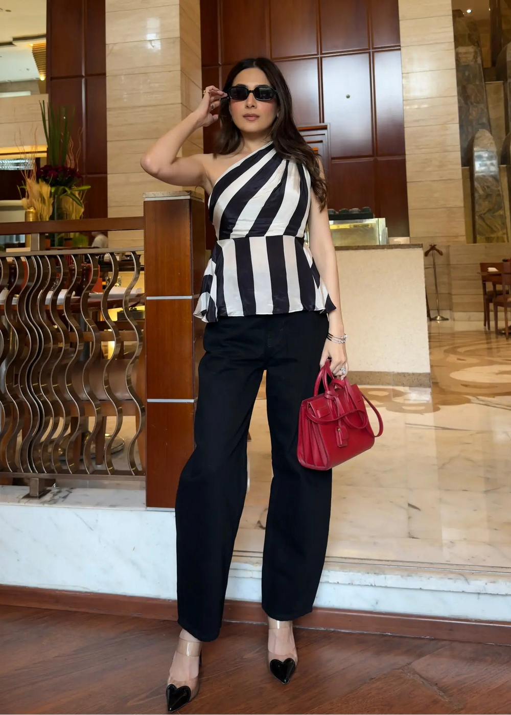 Woman in a black and white striped top and black pants standing in a hotel lobby.